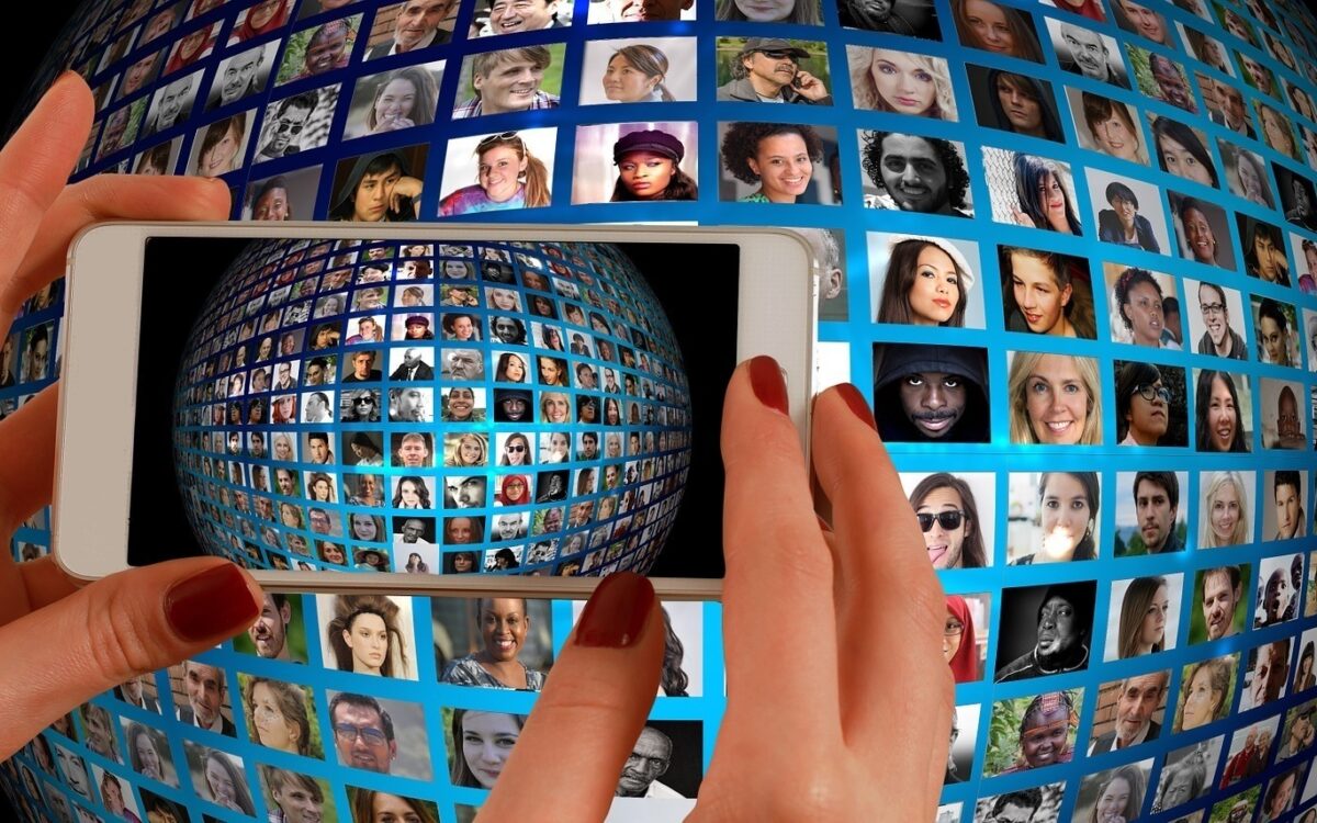 Zwei Hände halten ein Smartphone, darauf zu sehen viele Fotos von Menschen Zwei Hände halten ein Smartphone, darauf zu sehen viele Fotos von Menschen